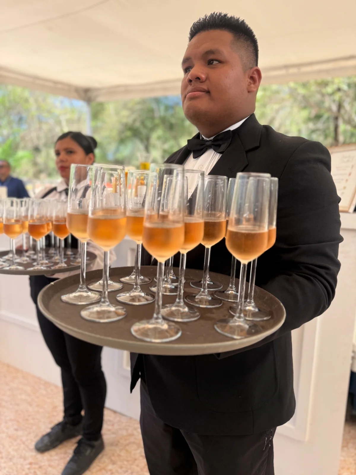 Mesero de AUTÉNTICO ofreciendo bebidas durante un evento.